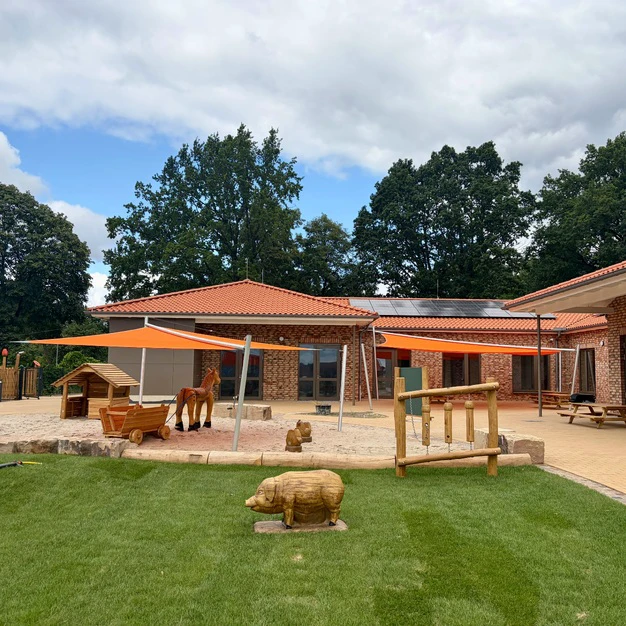 Ein einstöckiges Gebäude mit orangefarbenen Markisen und Tierstatuen auf dem Rasen