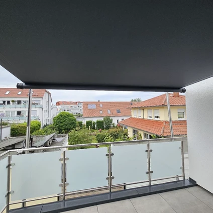 Balkon mit Glasgeländer und Dachüberstand Blick auf Gebäude einer Vorstadt