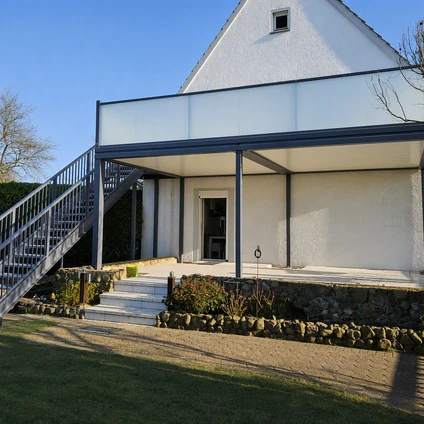 Modernes weißes Gebäude mit Glasanbau und externer Treppe auf einem grünen Rasen