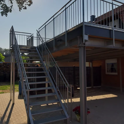 Metalltreppen und erhöhte Terrasse an einem Haus unter hellem Tageslicht