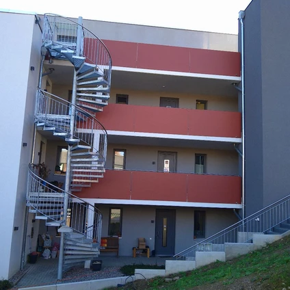 Modernes Apartmentgebäude mit Spiraltrappe roten und grauen Fassadendetails