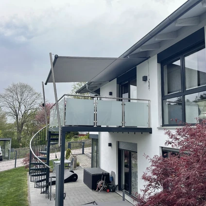 Modernes weißes Haus mit Balkon dunklen Überdachungen und auffälliger externer Spiraltreppe