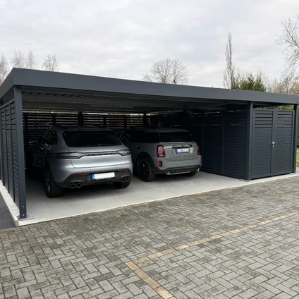 Zwei dunkle SUVs in einem modernen überdachten Carport auf einer gepflasterten Einfahrt